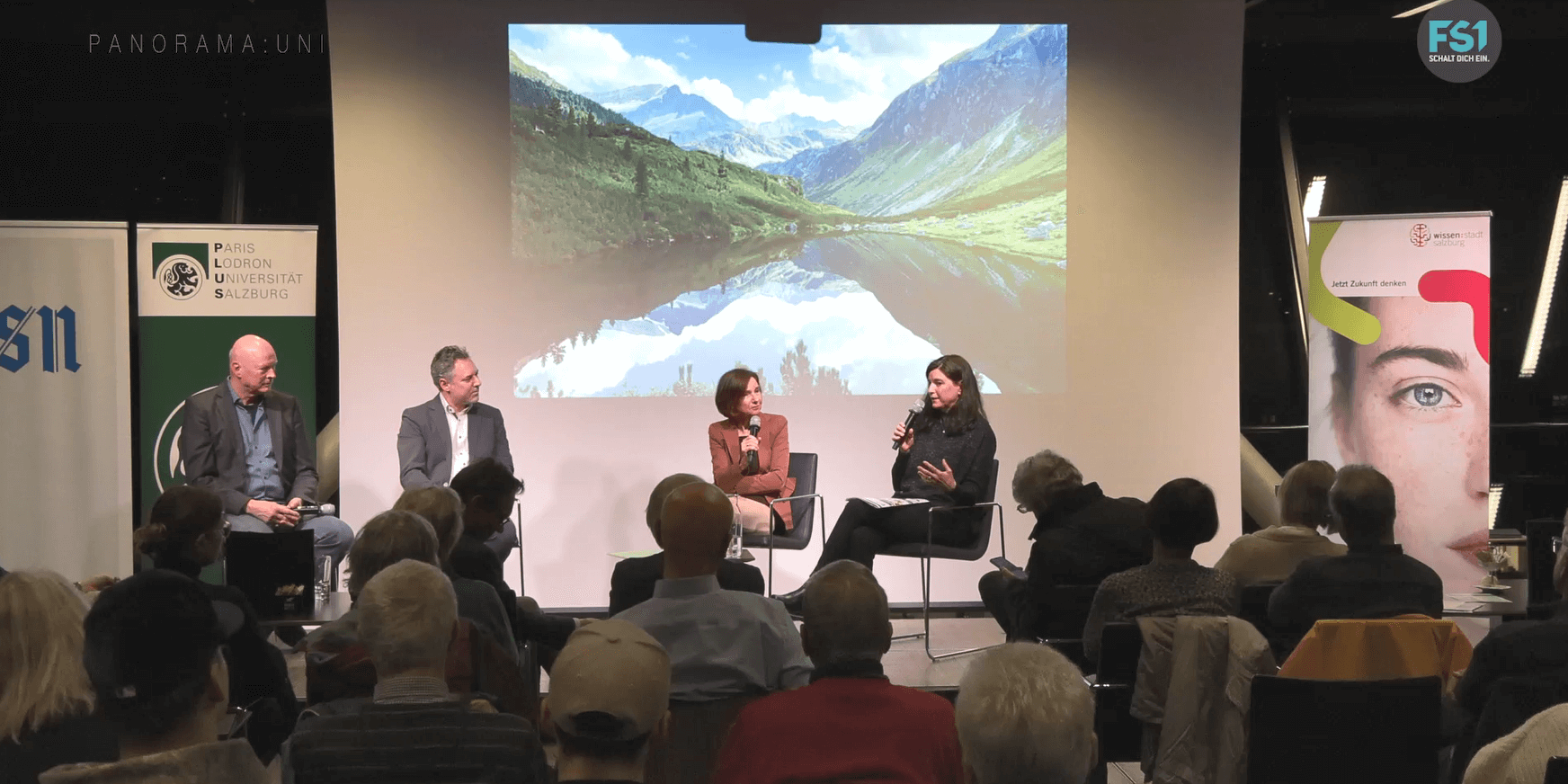 PanoramaUni_März_Podium_kl Panorma:Uni Nur noch kurz die Welt retten März 2025